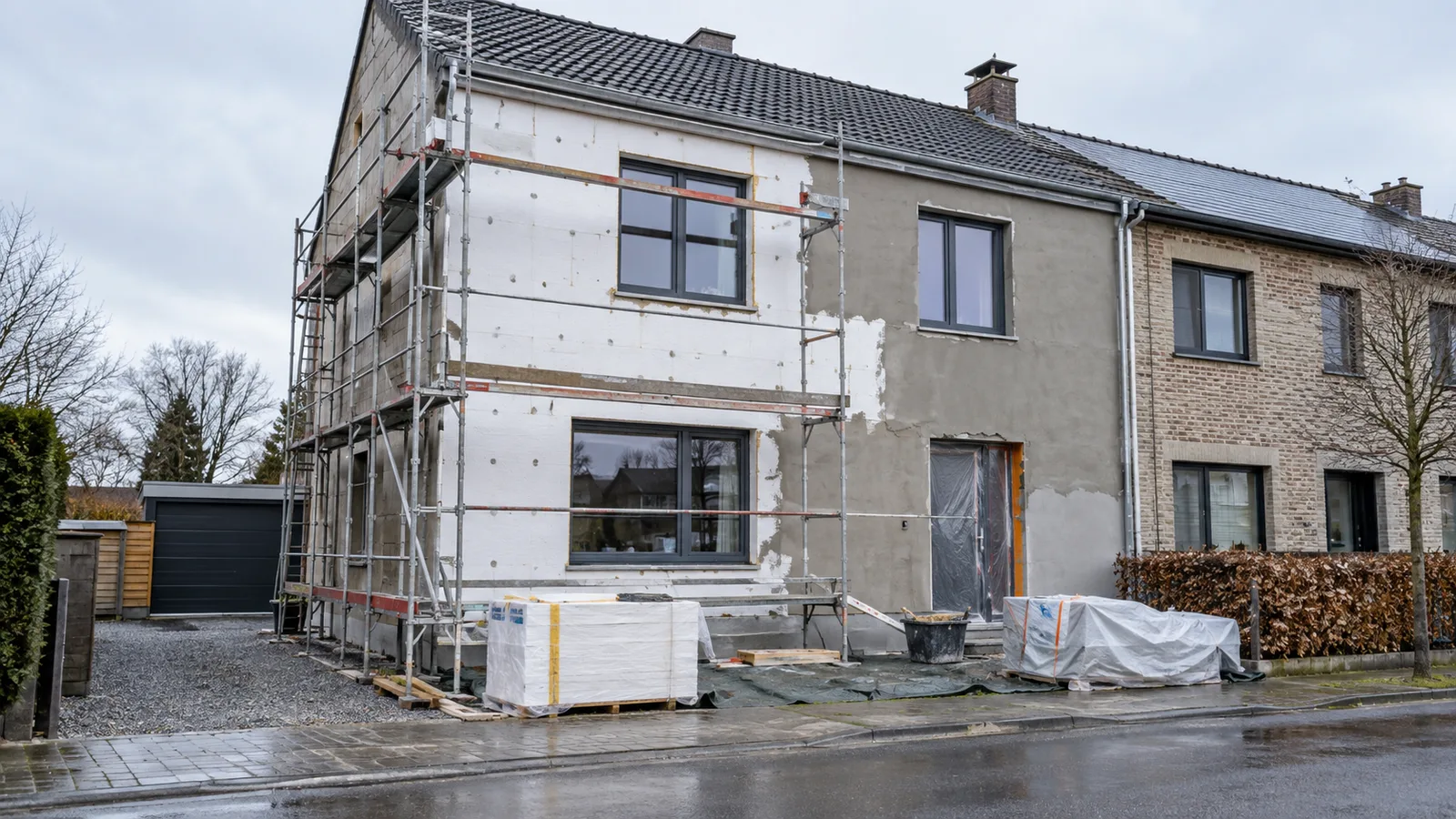 Façade mitoyenne à moitié isolée par panneaux blancs, échafaudage et châssis neufs